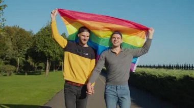 Gökkuşağı bayraklı neşeli gay adamlar dışarıda yürüyor