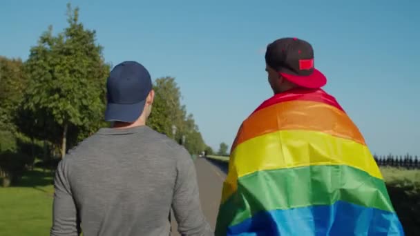 Pasangan gay bahagia dengan bendera pelangi berjalan di luar ruangan — Stok Video