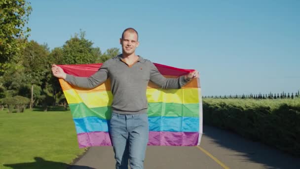 Dumny przystojny gej chodzenie z lgbt flaga na zewnątrz — Wideo stockowe