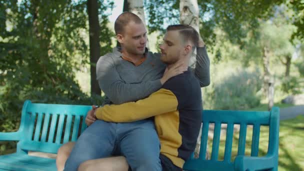 Kochający homoseksualni partnerzy wiążący się na ławce w parku — Wideo stockowe