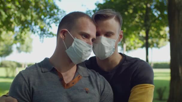 Koppel van hetzelfde geslacht in medische maskers zoenen buiten — Stockvideo