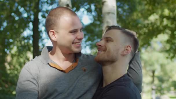 Щаслива гей пара на відкритому повітрі обіймає і посміхається — стокове відео