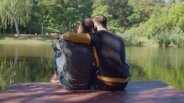 Vue arrière du couple gay embrassant sur jetée par lac — Video