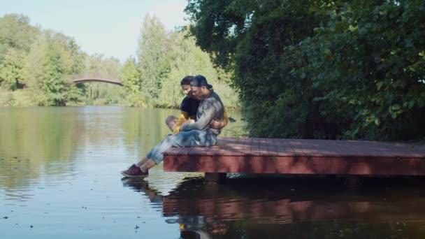 Positiva pareja del mismo sexo relajándose en el muelle junto al lago — Vídeo de stock