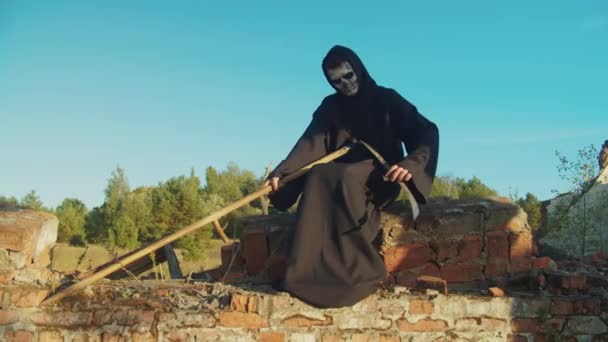 Grim Reaper afilando guadaña rústica al atardecer — Vídeo de stock