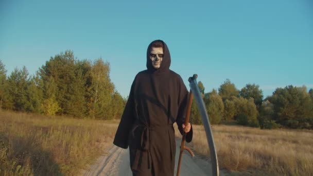 Death reaper frightening with scythe on dirt road — Stock Video