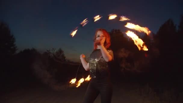 Mujer elegante haciendo malabares con los ventiladores de fuego en la noche — Vídeo de stock