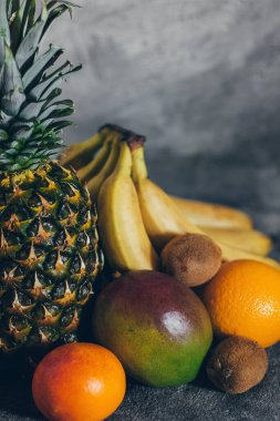Gri beton arka planda renkli taze tropikal meyveler.