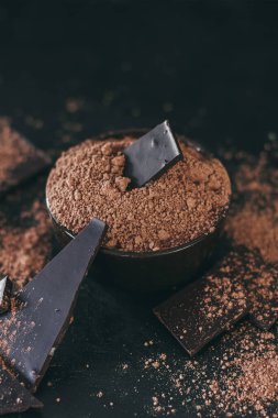 Kakao tozlu çikolata parçaları koyu arka planda, başa çıkma alanı.