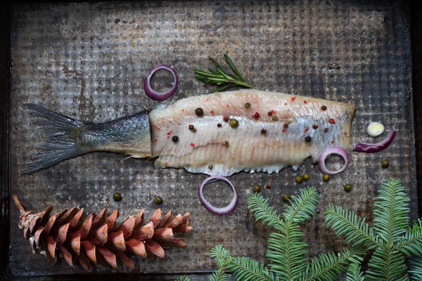 Abstract herring fish with spices and christmas ornament on metal plate creative still life