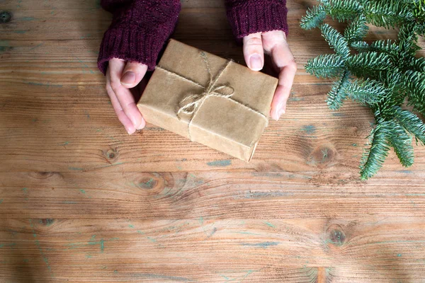 Ansicht Von Frauenhänden Mit Einfacher Geschenkschachtel Und Tannenbaum Auf Holzgrund — Stockfoto