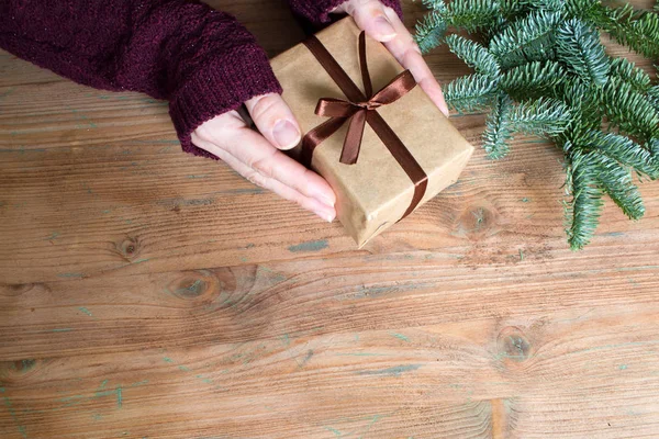 Ansicht Von Frauenhänden Mit Einfacher Geschenkschachtel Und Tannenbaum Auf Holzgrund — Stockfoto