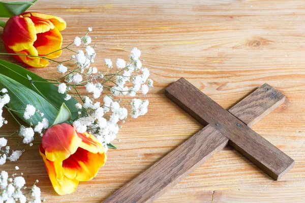 Spring easter flowers and cross on wooden background