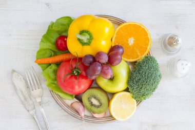 Tabak dolusu meyve ve sebze, çatal bıçak, baharat. Sağlıklı yemek kavramı