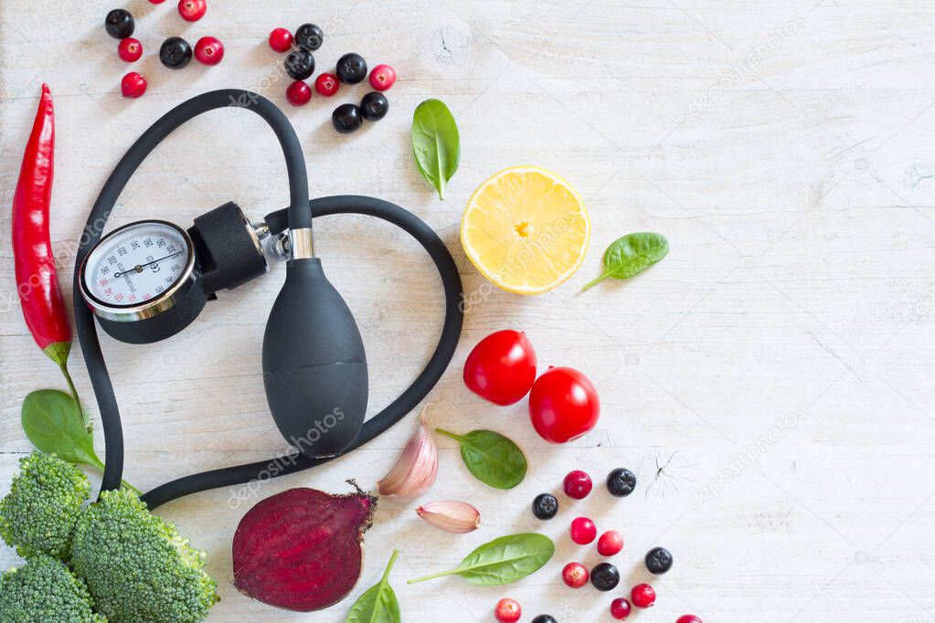 Heart-shaped blood pressure monitor and vegetables with fruits to prevent hypertension, healthy diet concept