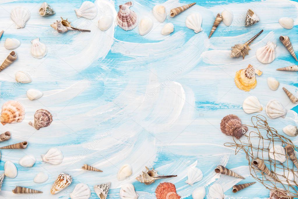 Sea shells and fishing net on blue wooden board. Maritime flat lay with copy space