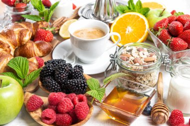 Kahvaltı kahve, kruvasan, müsli, taze meyve, çilek, portakal, elma, süt ile. Sağlıklı gıda kavramı