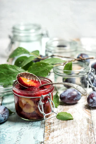 Plums marmalade in jar. Fruit jam on rustic wooden background