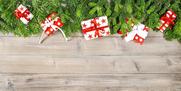 红色圣诞礼物和绿色松树树枝棕色木背景 — 图库照片