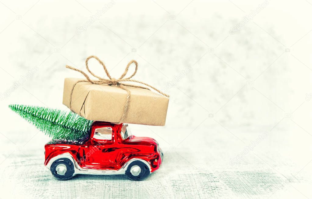 Red car with gift box and Christmas tree. Vintage toned picture