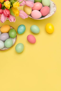 Paskalya yumurta dekorasyon ve sarı arka plan üzerinde renkli Lale çiçek