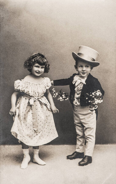 Photo of funny little girl and boy in vintage dressing. Retro picture with original film grain and scratches