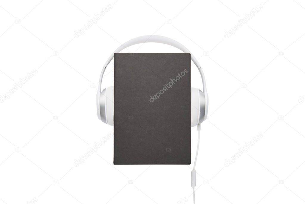 Audio book concept. Black book and white headphones set isolated on white background with copy space.