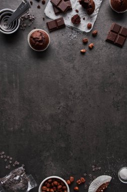Arka plan ile ölçme bardak, çikolata, şeker ve karanlık beton zemin üzerine fındık çikolata muffins pişirme. Kopya alanı orta düz yatırın.