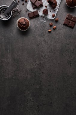 Arka plan ile ölçme bardak, çikolata, şeker ve karanlık beton zemin üzerine fındık çikolata muffins pişirme. Kopya alanı altındaki düz yatırın.