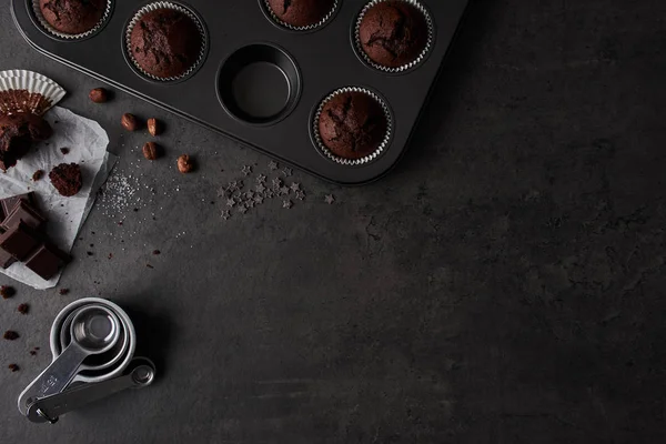 Arka plan ile tasarlayacağım, ölçme bardak, çikolata, şeker ve karanlık beton zemin üzerine fındık çikolata muffins pişirme. Düz kopya alanı ile yatıyordu.