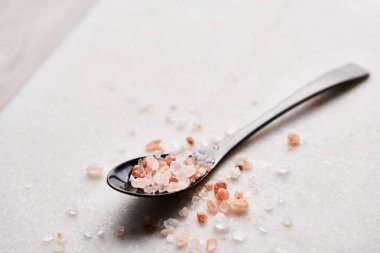 Siyah kaşık pembe Himalaya tuz kopya alanı ile mermer tabloda. Yakın çekim.