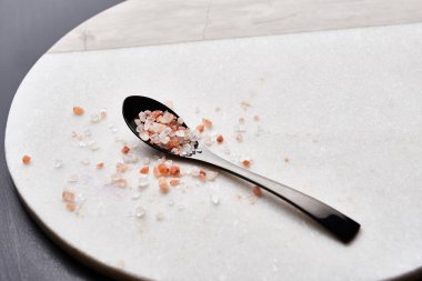 Pembe Himalaya tuz kopya alanı ile mermer kesme tahtası üzerinde siyah kaşık.