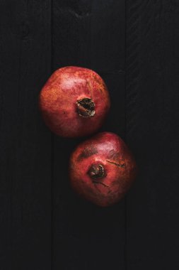Düz iki olgun nar meyve siyah ahşap antika arka plan üzerinde yatıyordu. Kopya alanı ile üstten görünüm.