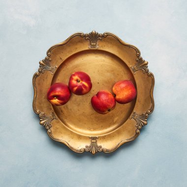 Düz taze nektarin meyve üzerinde açık mavi renkli rustik altın servis tabağı üzerinde yatıyordu. Üstten görünüm, kare kırpma.