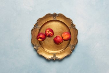 Düz taze nektarin meyve üzerinde açık mavi renkli rustik altın servis tabağı üzerinde yatıyordu. Kopya alanı ile üstten görünüm.