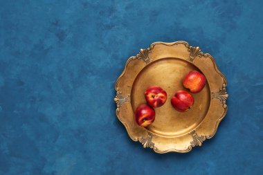 Düz taze nektarin meyve rustik altın servis tabağı üzerinde mavi arka plan üzerinde yatıyordu. Kopya alanı ile üstten görünüm.