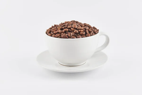 Vit Kaffekopp Fylld Med Hela Kaffebönor Ett Tefat Isolerad Vit — Stockfoto