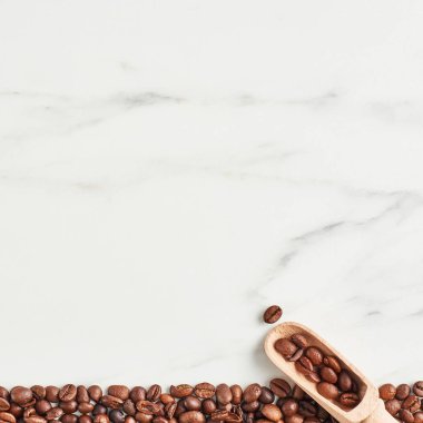 Kahve çekirdekleri ve kopya alanı mermer zemin üzerine ahşap kepçe. Düz yatıyordu, kare kırpma.