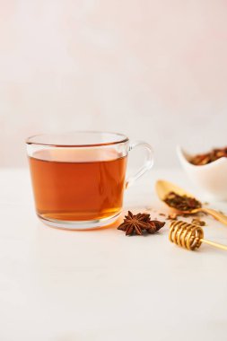 Siyah çay otlar, kepçe ve anason mermer masa üstü üzerinde altın kaşıkla bir cam fincan. Kadınsı gül arka plan kopya alanı ile. Dar alan derinliği.