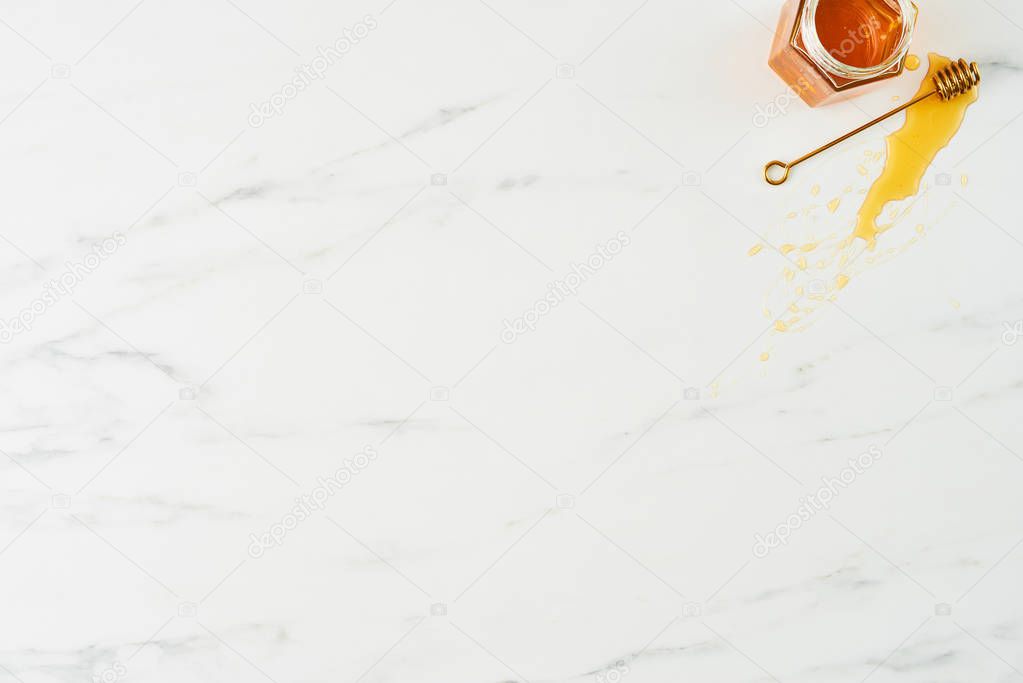 Honey concept. Top view of golden dipper with honey and jar on white marble background. Horizontal flat lay with copy space.