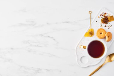 Çay mesure ve plaka hizmet üzerinde bal ile Altın Ayı'yı üstten görünüm beyaz fincan çay, bisküvi, otlar. Fincan çay beyaz mermer zemin üzerinde. Düz kopya alanı ile yatıyordu.