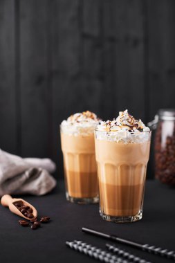 Karamel latte kahve çikolata şurubu ve krem şanti ile uzun bir bardak buzlu. Koyu ahşap arka plan kopya alanı ile.