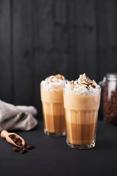 Karamel latte kahve çikolata şurubu ve krem şanti ile uzun bir bardak buzlu. Koyu ahşap arka plan kopya alanı ile.