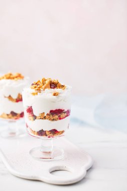 Sağlıklı ahududu yoğurt parfe pembe arka plan kopya alanı ile üzerine beyaz mermer masada bir bardak.