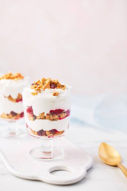 Sağlıklı ahududu yoğurt parfe pembe arka plan kopya alanı ile üzerine beyaz mermer masada altın kaşıkla bir cam.