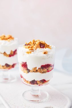 Kopya alanı ile pembe arka plan üzerinde beyaz mermer masada bir bardak sağlıklı ahududu yoğurt parfait, yakın çekim.