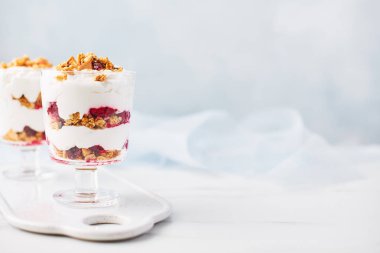 Bir bardak beyaz mermer masa üzerinde kopya alanı ile açık mavi renkli üzerinde sağlıklı ahududu yoğurt parfe.