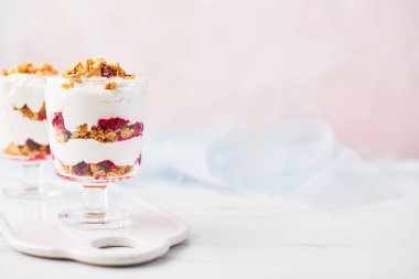 Sağlıklı ahududu yoğurt parfe pembe arka plan kopya alanı ile üzerine beyaz mermer masada bir bardak.