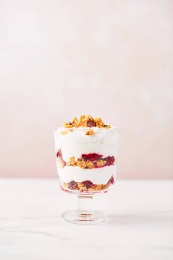 Sağlıklı ahududu yoğurt parfe pembe arka plan kopya alanı ile üzerine beyaz mermer masada bir bardak.