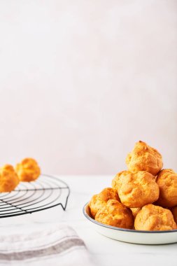 Bir avuç taze kremalı pasta kek beyaz mermer masa kopya alanı ile pembe arka plan üzerinde beyaz bir levha ve tel raf üzerinde. Seçici odak.